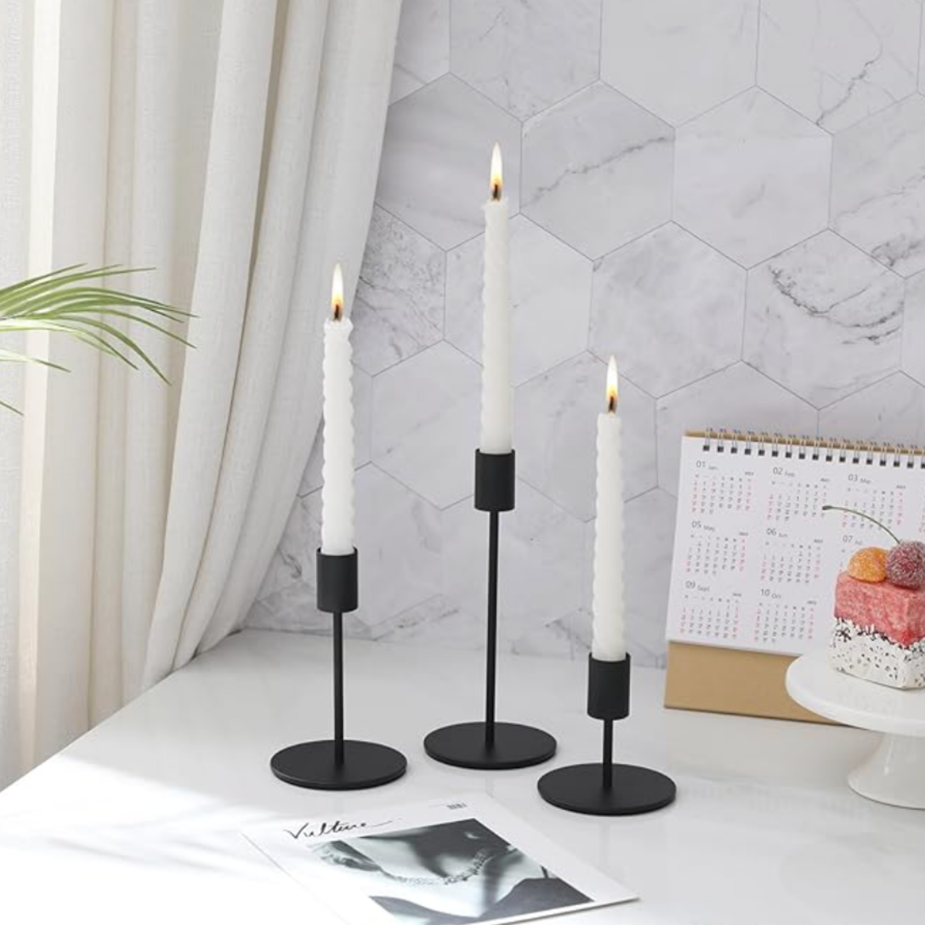 Black taper candle holders with white candles styled as modern tabletop decor.