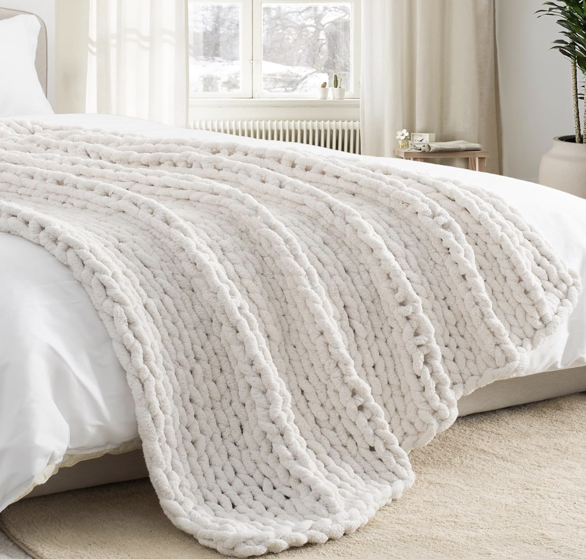 Cozy bedroom styling with a plush textured blanket, natural light, greenery and neutral home decor.