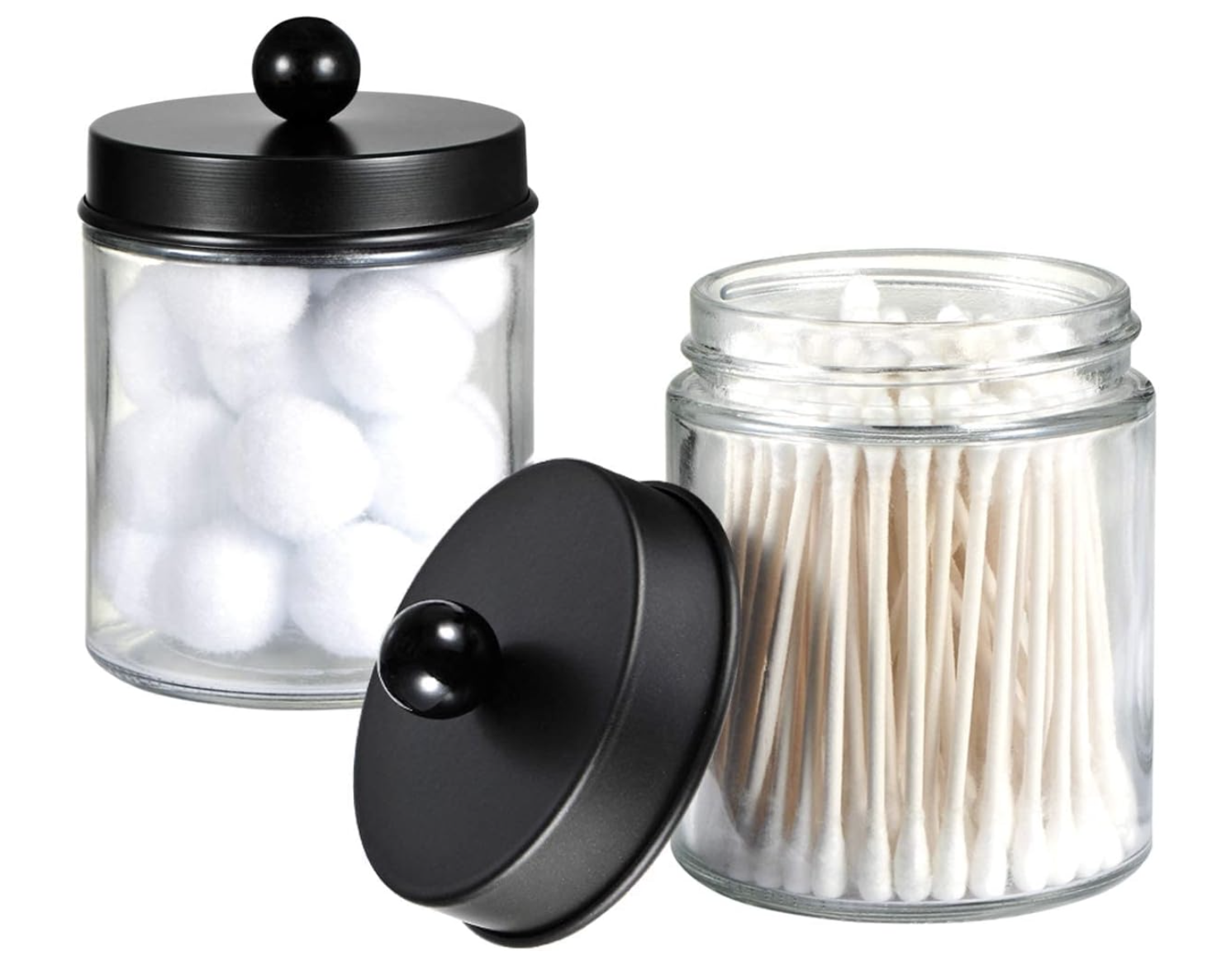 Glass bathroom storage jars with black lids for cotton balls and personal care essentials.