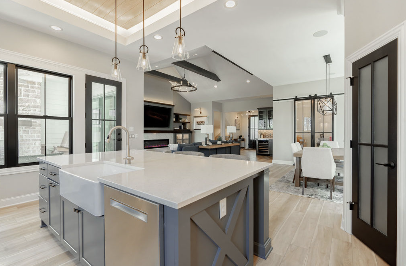 Modern kitchen with a white farmhouse sink and island, opening into a living room and dining area.
