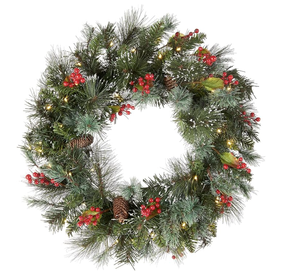Decorative Christmas wreath with pine branches, red berries, pinecones and warm lights for curated holiday home decor.