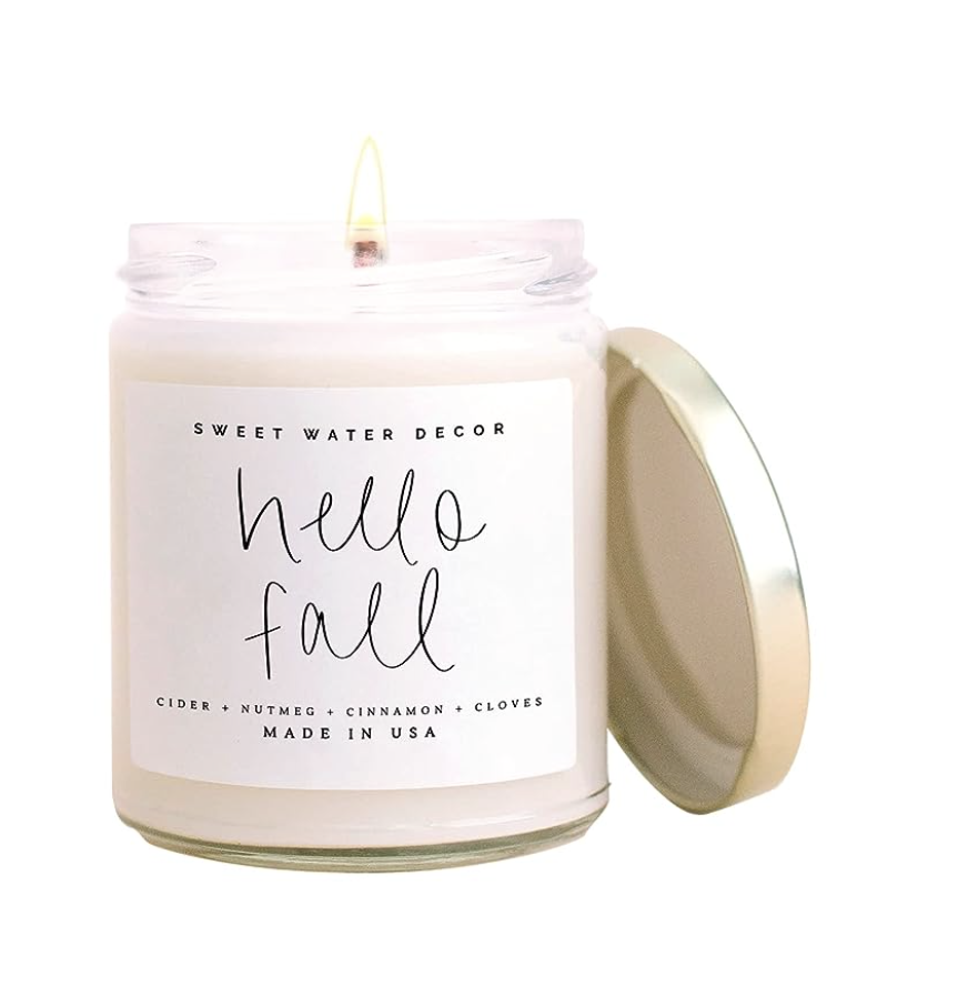 Lit “Hello Fall” scented candle in a glass jar with a gold lid.