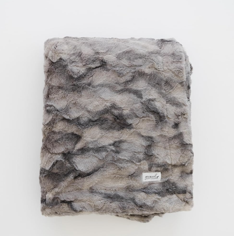 Neutral faux fur blanket in gray and beige tones for cozy bedroom and living room styling.