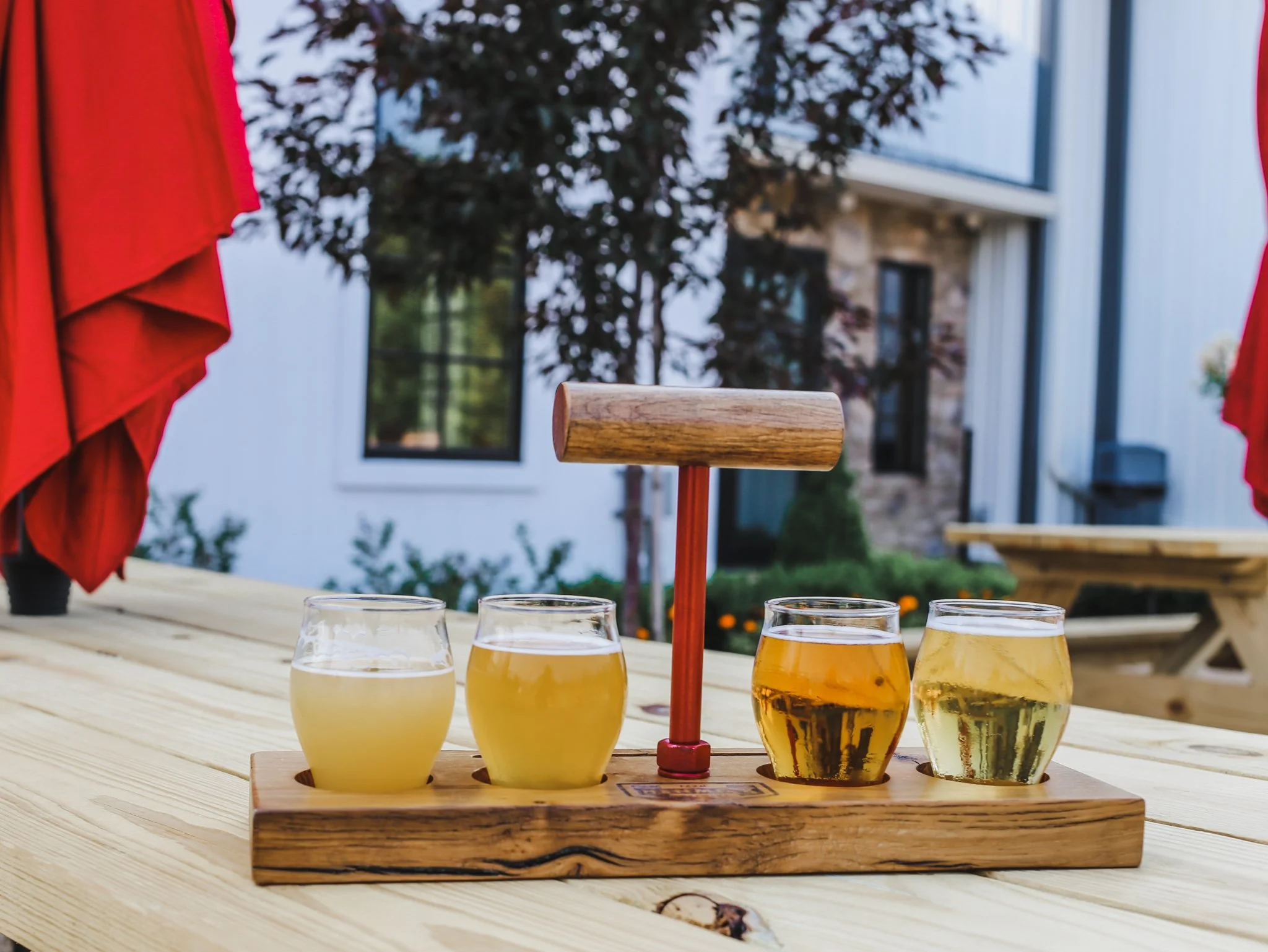 A beer flight with four different glasses on a wooden paddle.