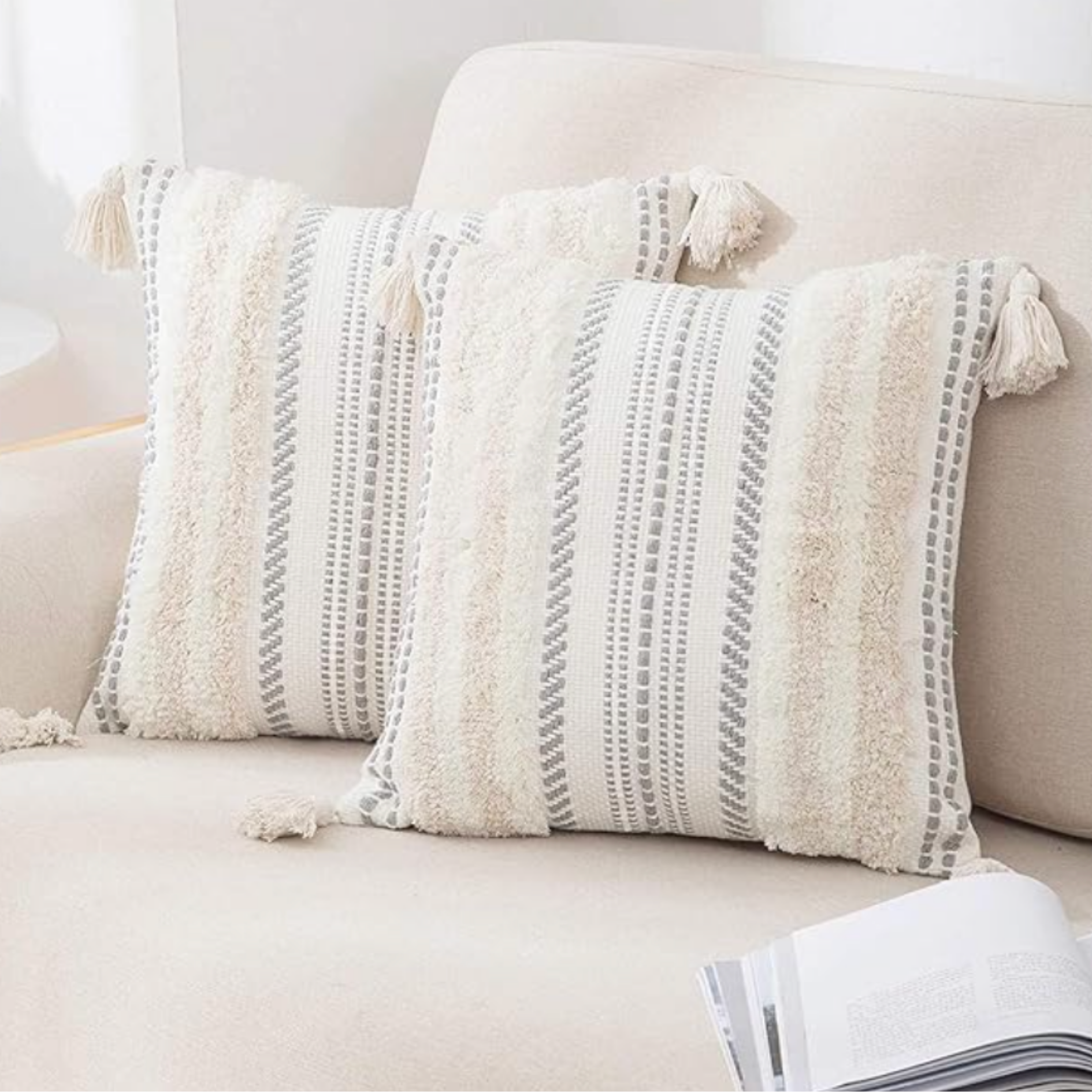 Neutral bedroom styling featuring textured white bedding and layered decorative throw pillows.