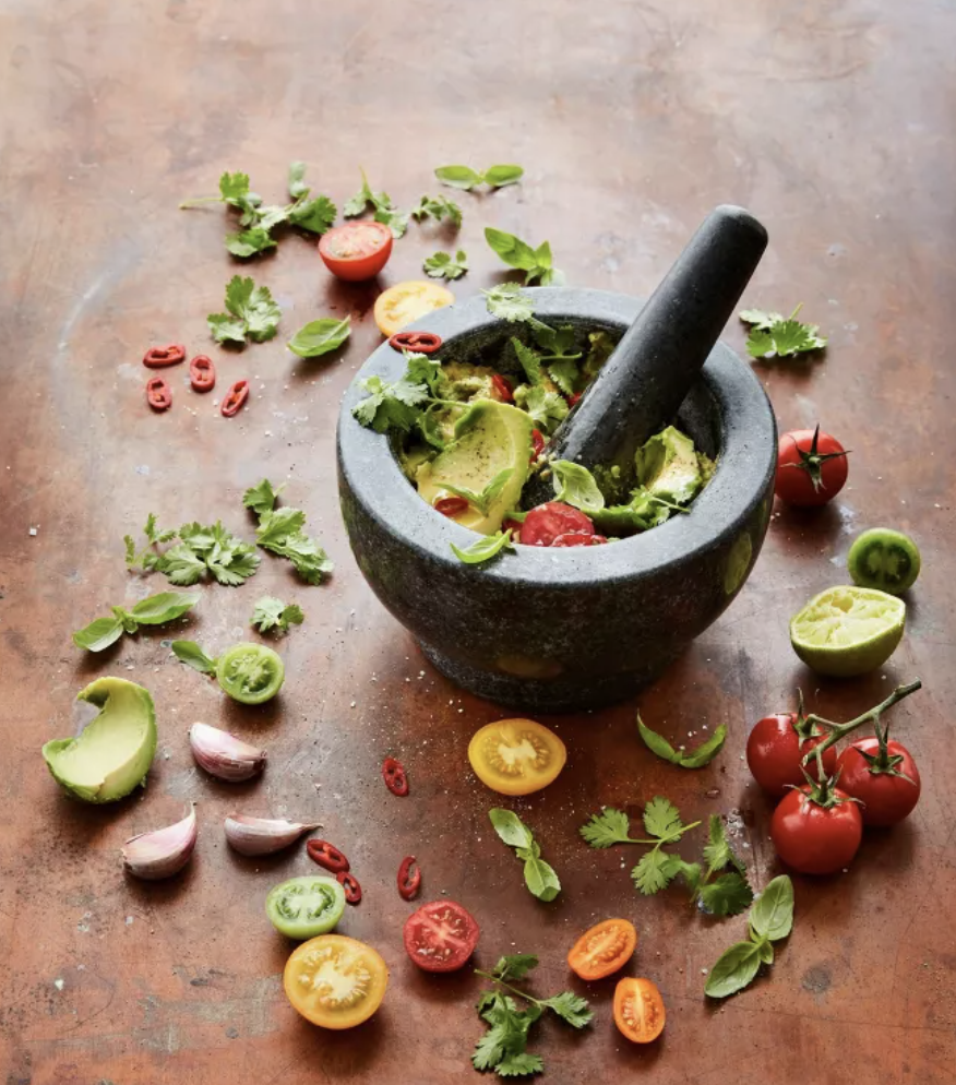 Fresh tomatoes, herbs and vegetables styled around a mortar and pestle for kitchen entertaining.