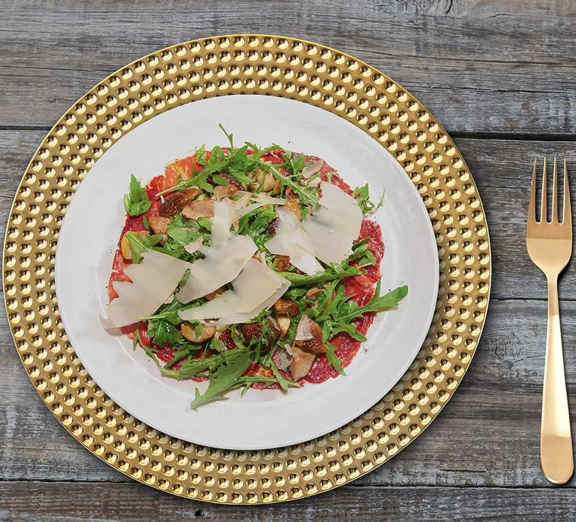 Steak tartare plated with arugula, cheese and nuts on gold-rimmed dinnerware for home entertaining inspiration.