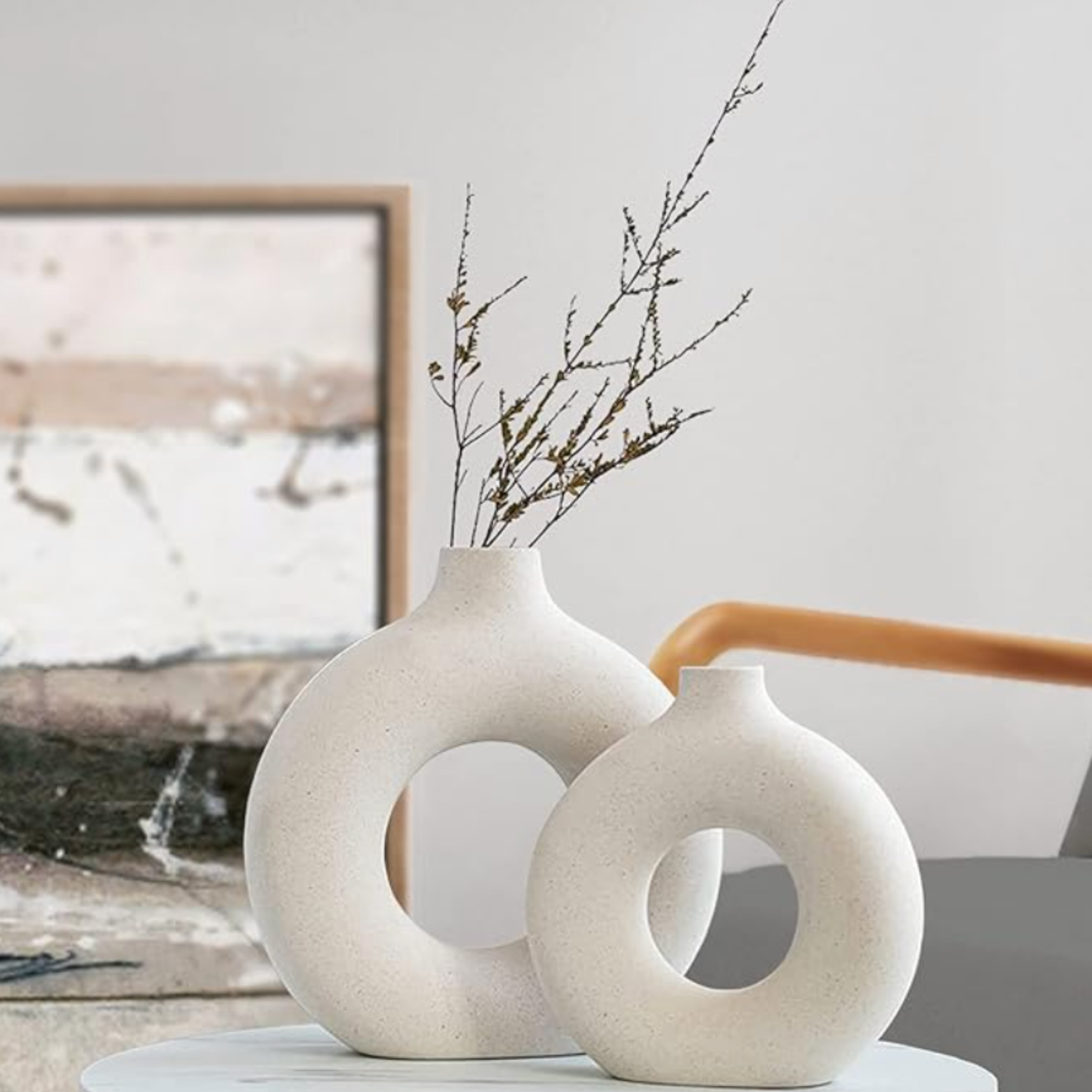 White ceramic vase with dried branches styled with natural wood and neutral home decor.