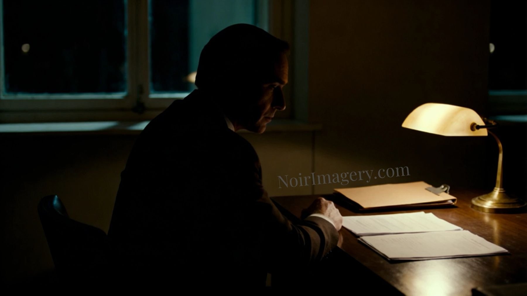 A man seated at a desk reviewing papers under a single lamp in a dimly lit noir office.