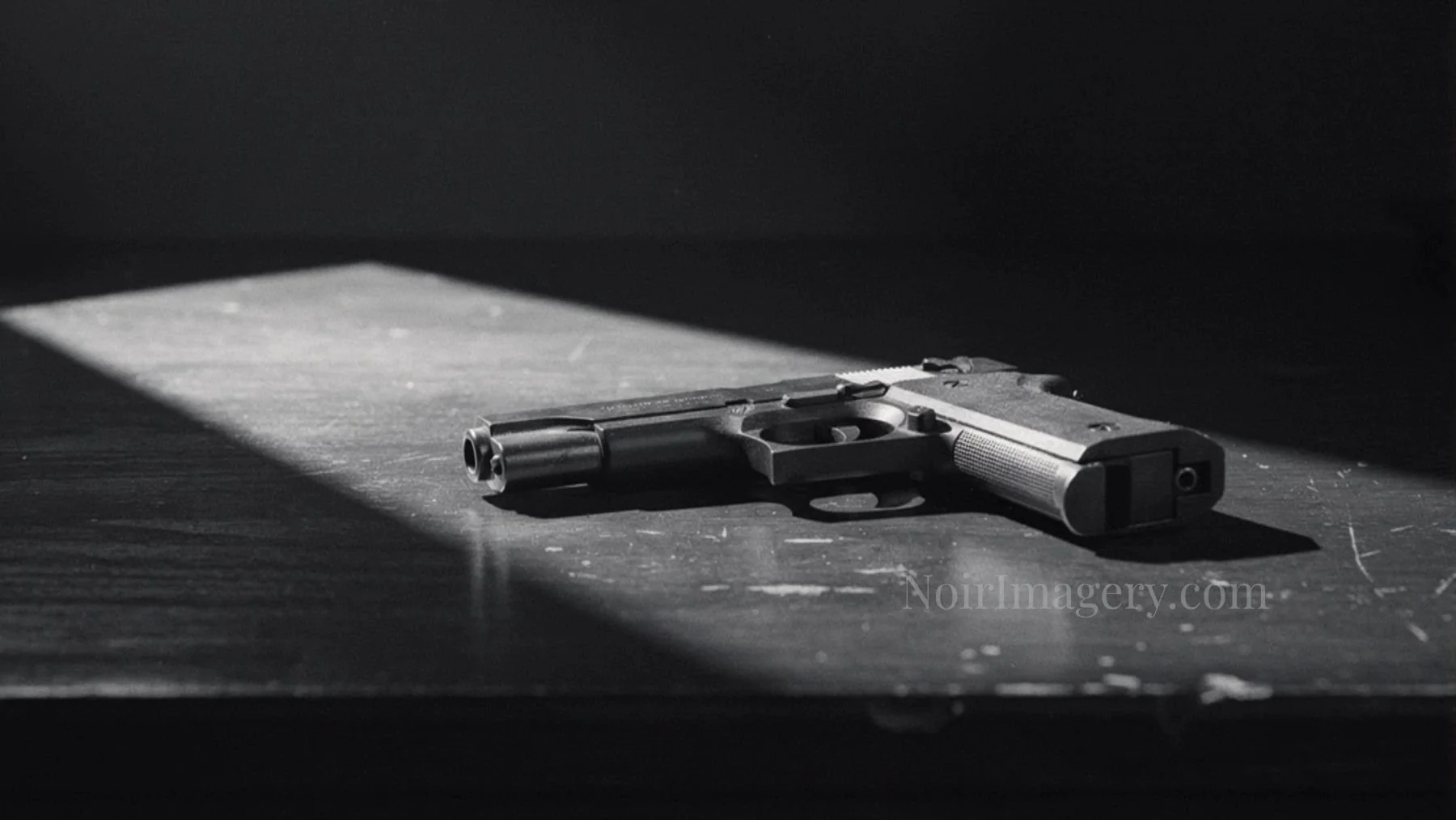 Black and white noir image of a handgun resting on a wooden table under a harsh beam of light