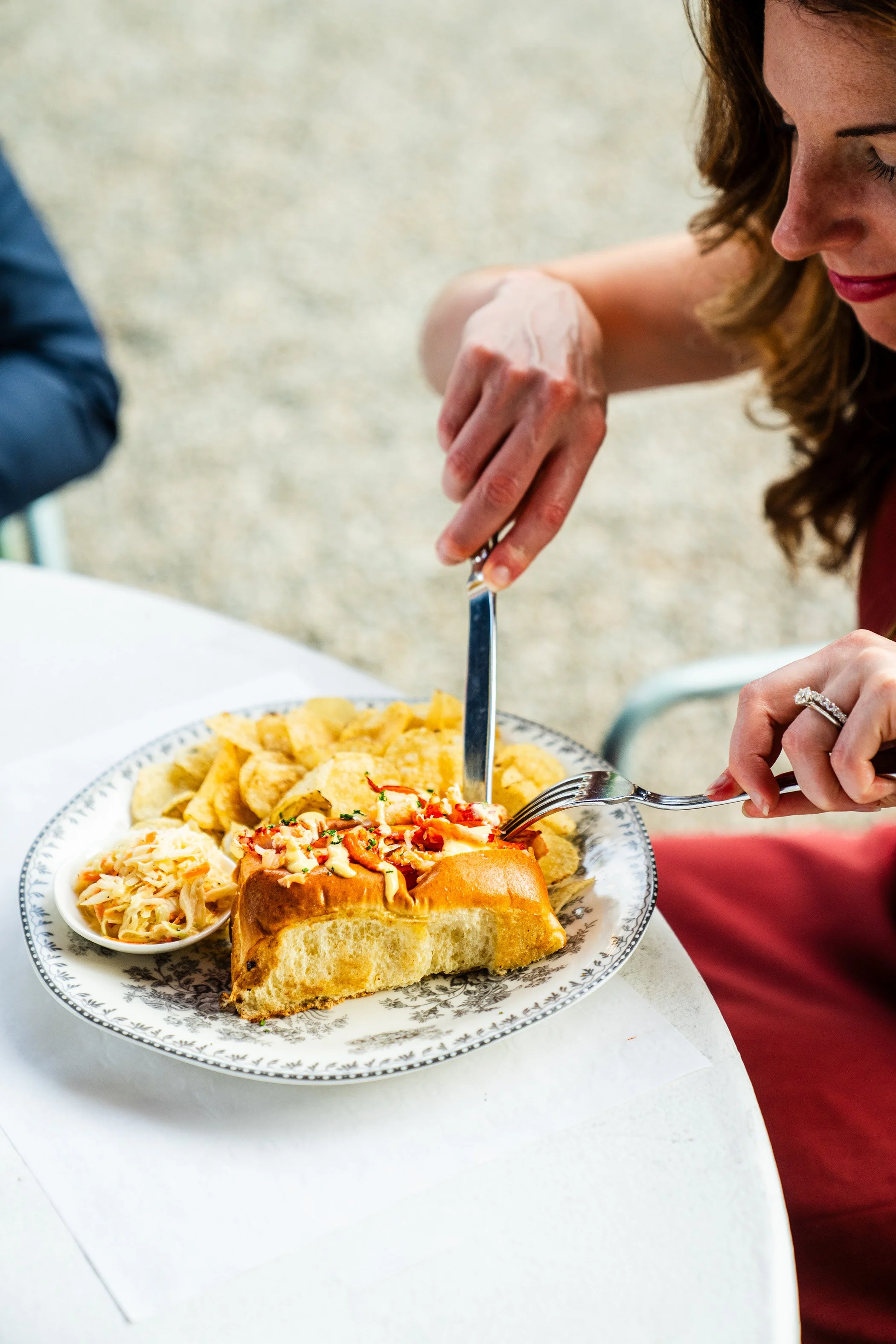 Person serving themselves food at a meal, with a plate of pasta, bread, and other dishes on a table.