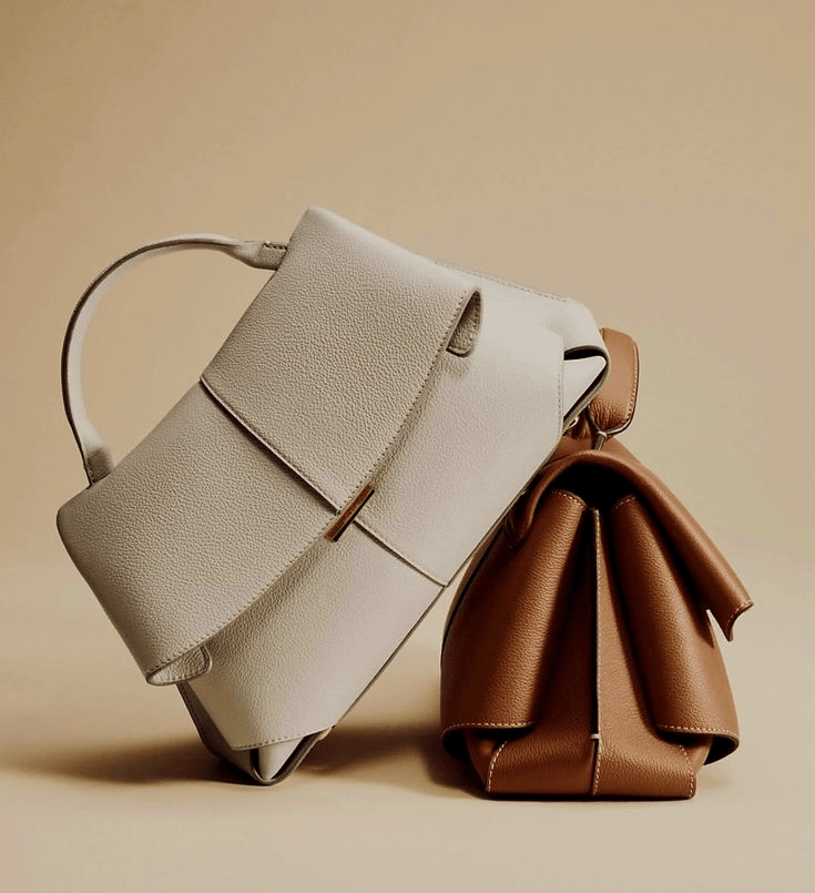 Two leather handbags, one in white and one in brown, placed against a beige background.