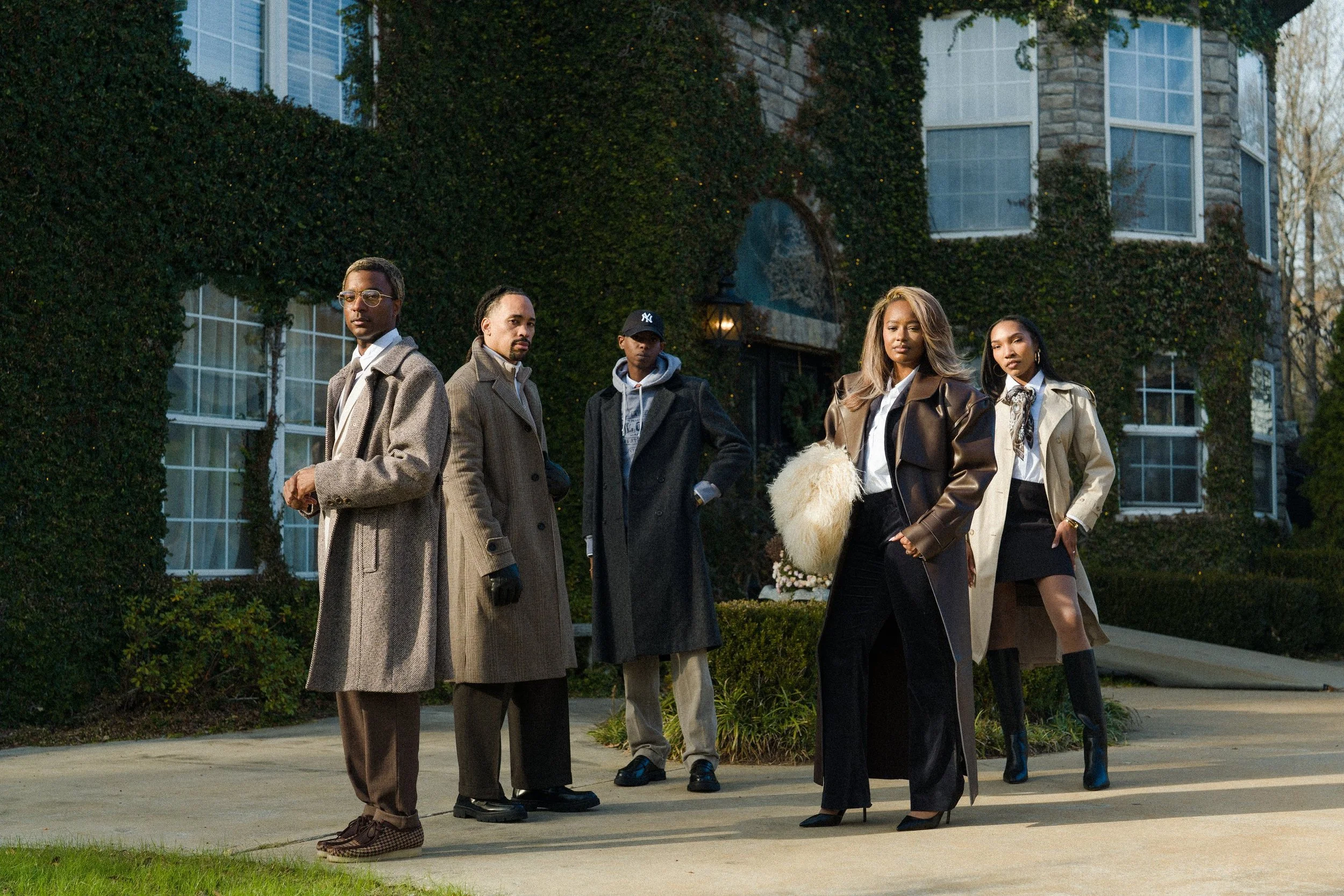 Six fashionable individuals standing in front of a large, ivy-covered building, posing confidently for the camera.