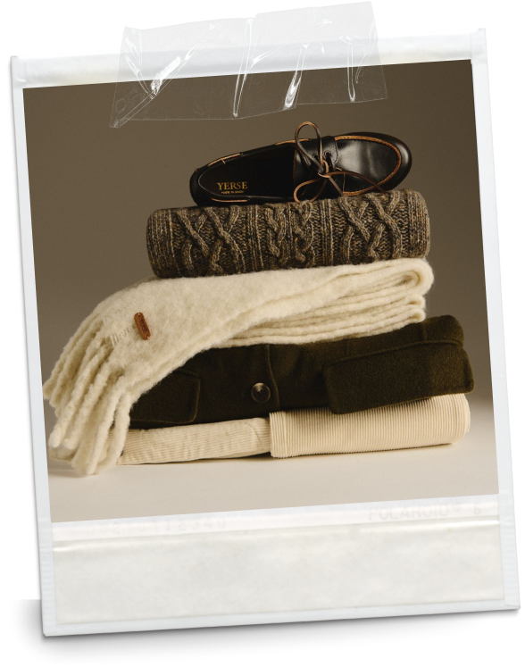 Stack of folded clothes including two sweaters and a pair of shoes on top, with clear tape at the top of the image.