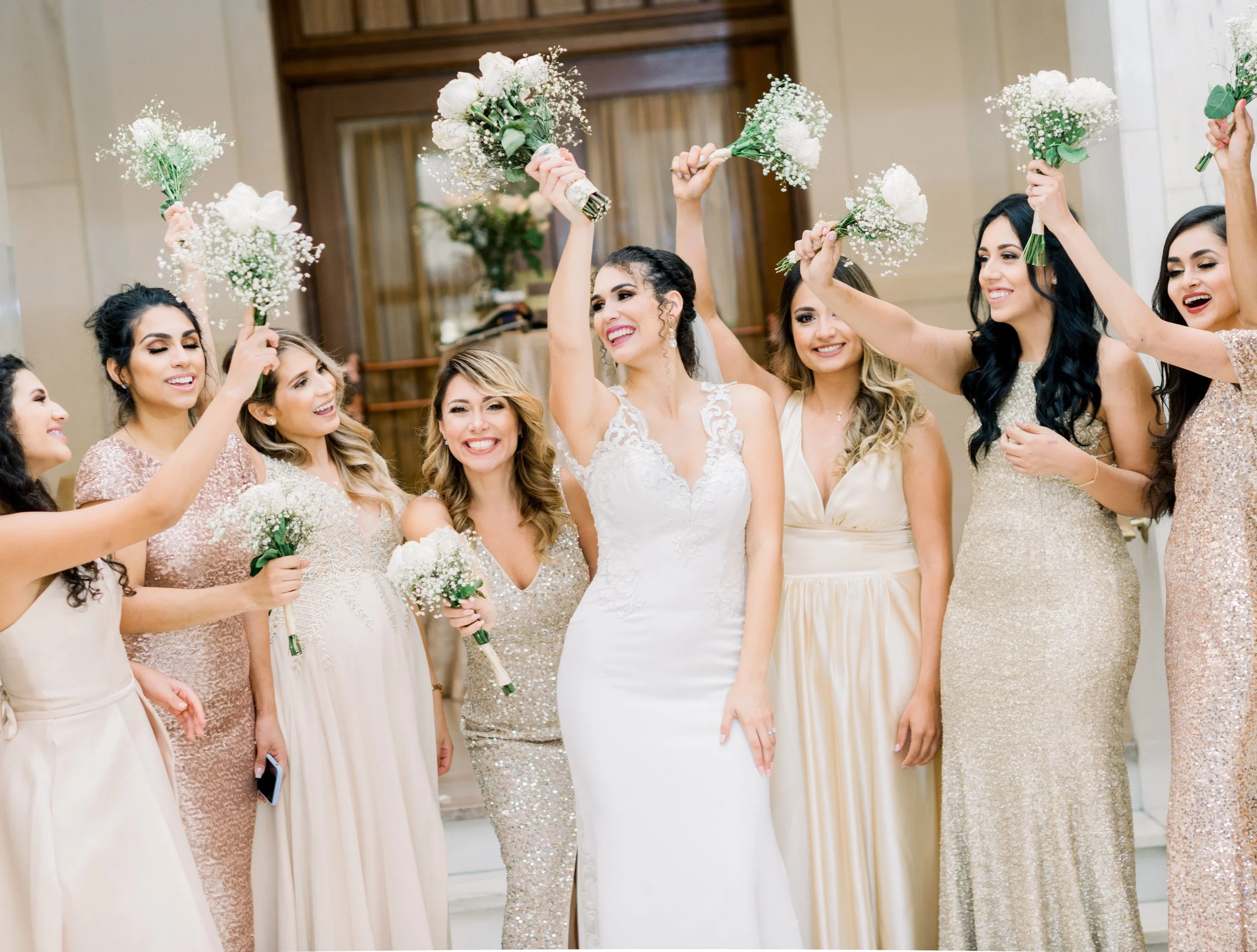 Bride and bridesmaids celebrating with bouquets at a wedding reception