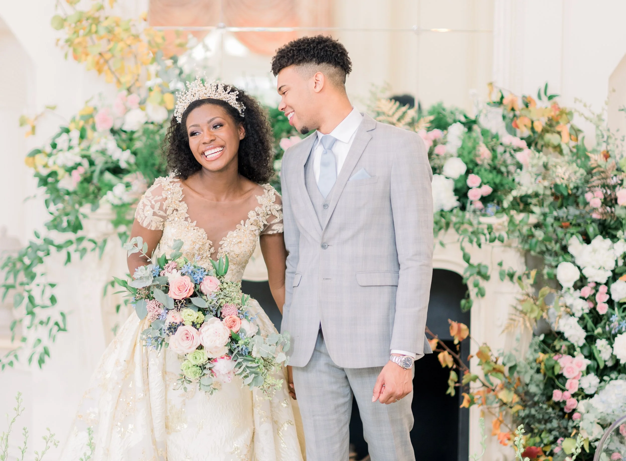 A bride and groom smiling at each other during their wedding ceremony, surrounded by floral decorations.