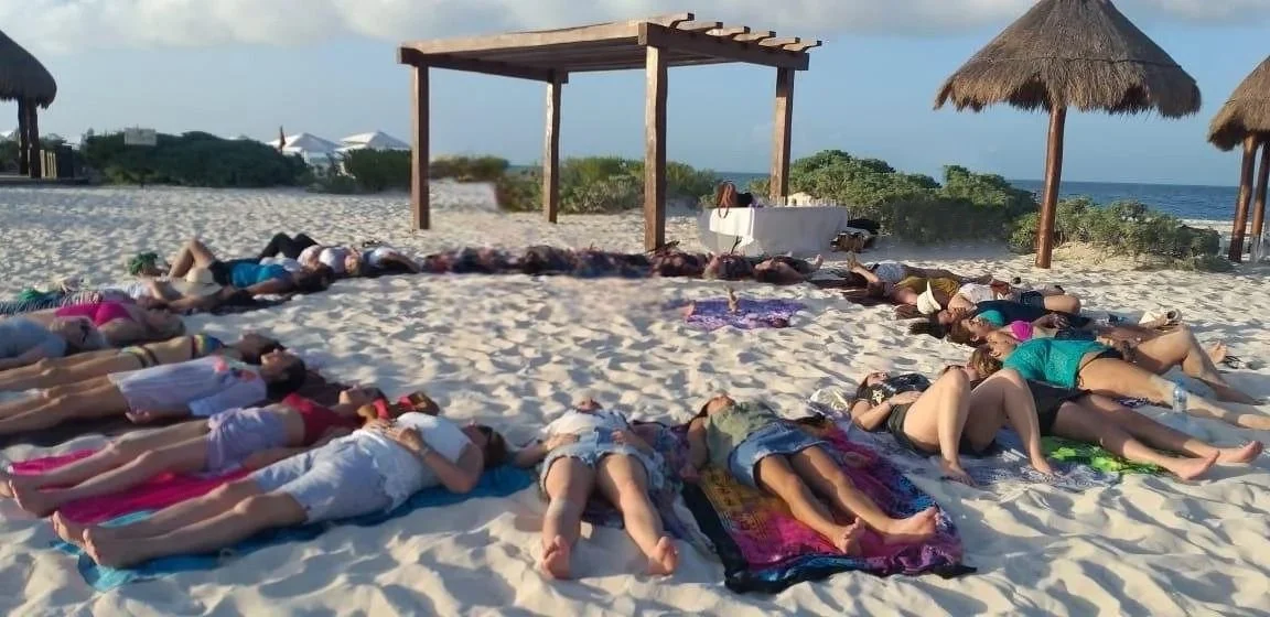 Grupo de personas practicando yoga en la playa