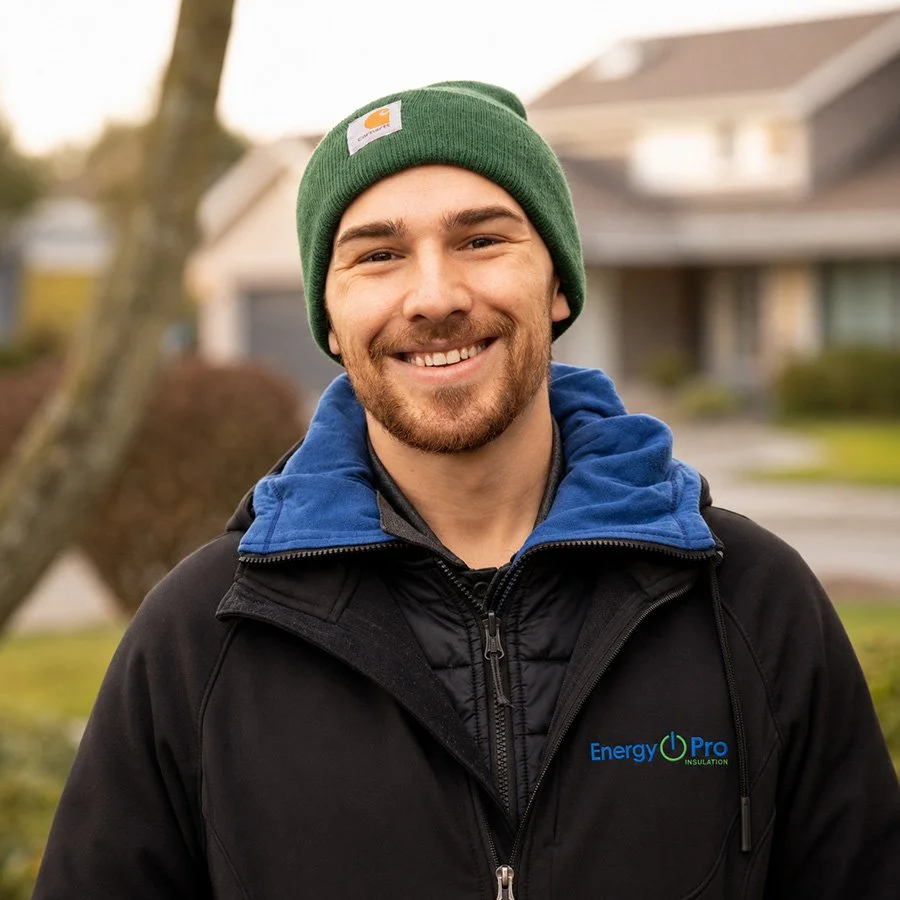 A smiling young man outdoors wearing a green beanie, a blue hoodie, and a black jacket with the 'Energy Pro Insulation' logo.