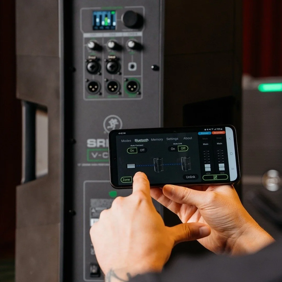 Person adjusting Bluetooth settings on a smartphone controlling an audio system with multiple input ports.