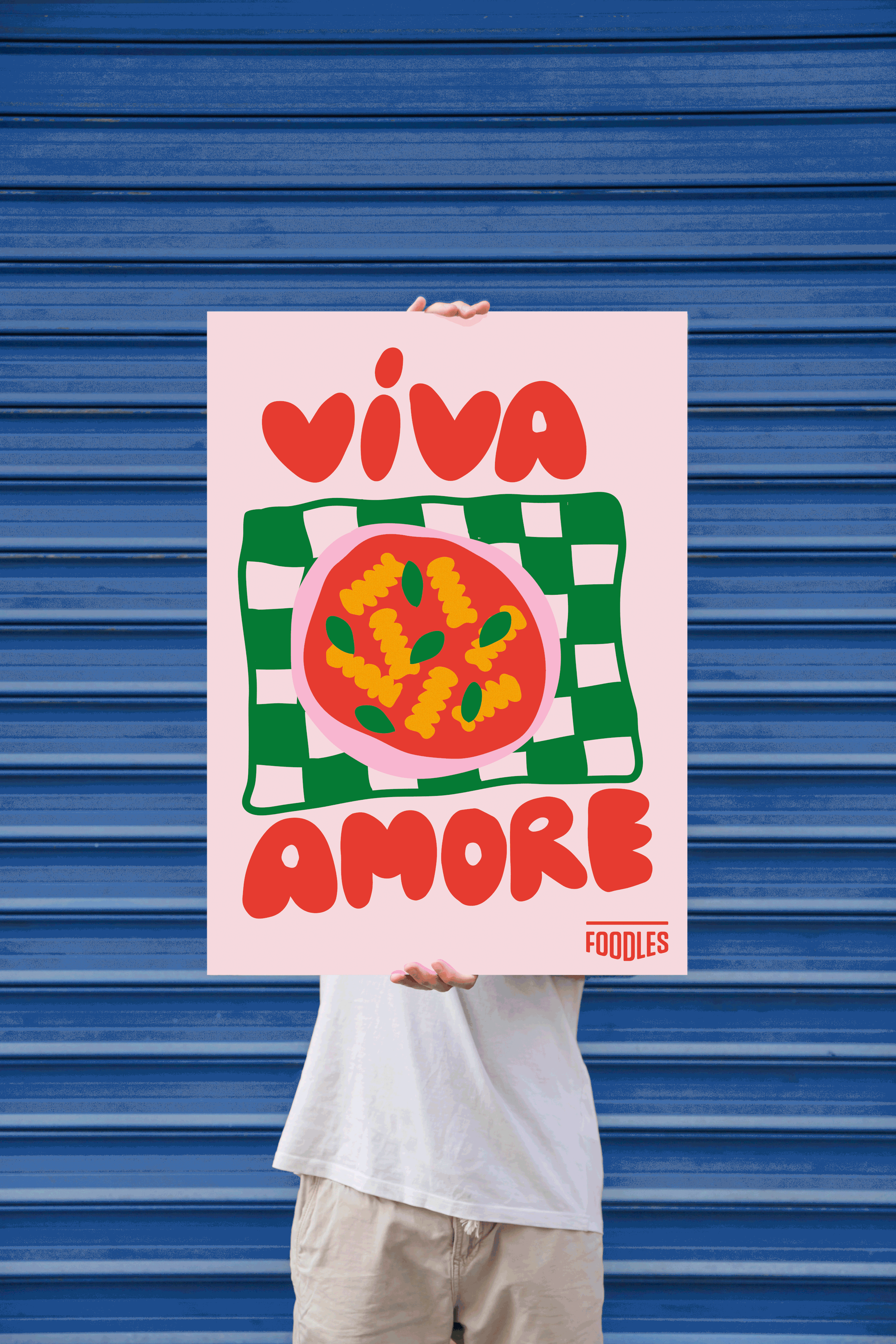 Person tenant une affiche colorée avec une pizza et les mots 'Viva Amore' et 'Foodles' contre un rideau bleu.