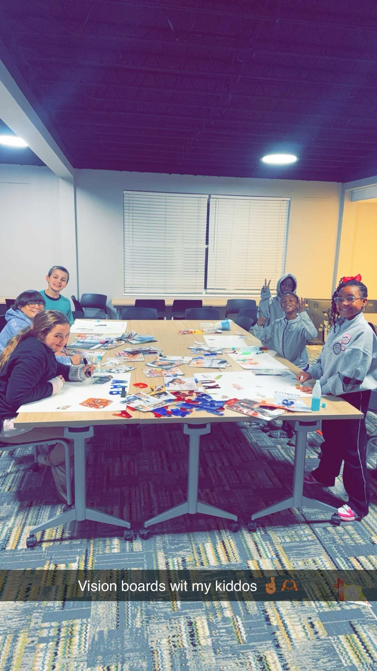 Group of children working on vision boards at a table with magazines, glue, and craft supplies.
