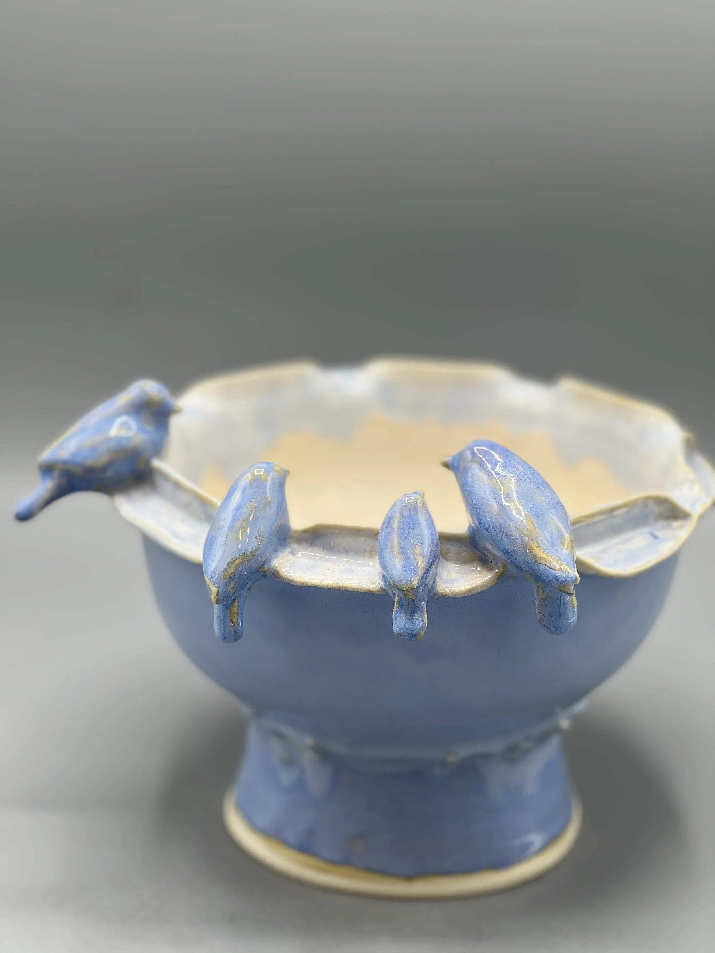 Porcelain pedestal bowl with 4 small blue birds perched on the rim.