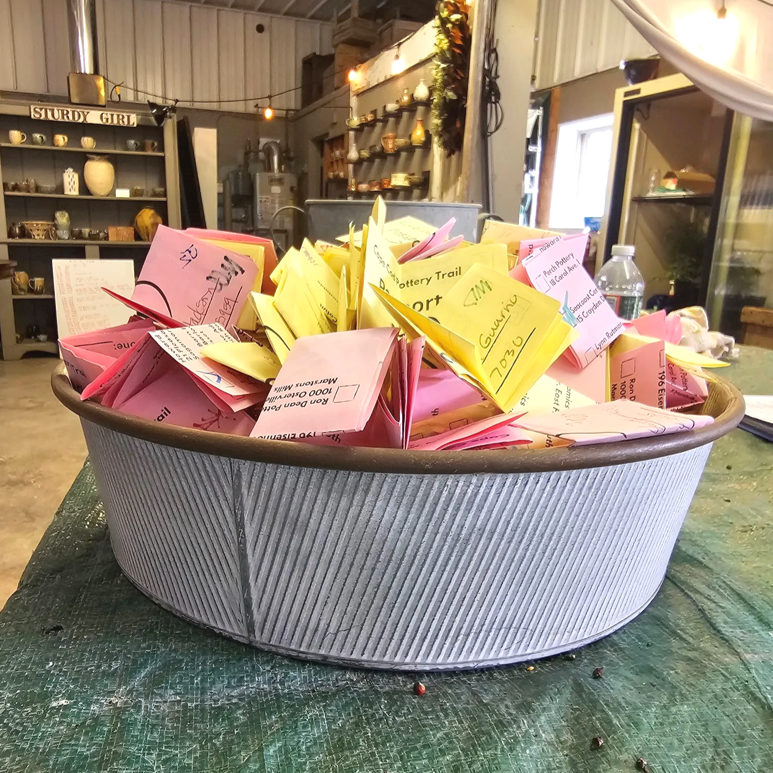 A large round container filled with stamped pottery passports. Get your passport stamped and enter to win prizes!