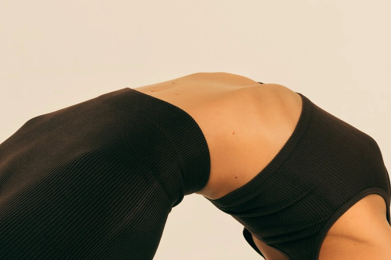 Arched torso in black activewear, representing supported movement and chiropractic wellness