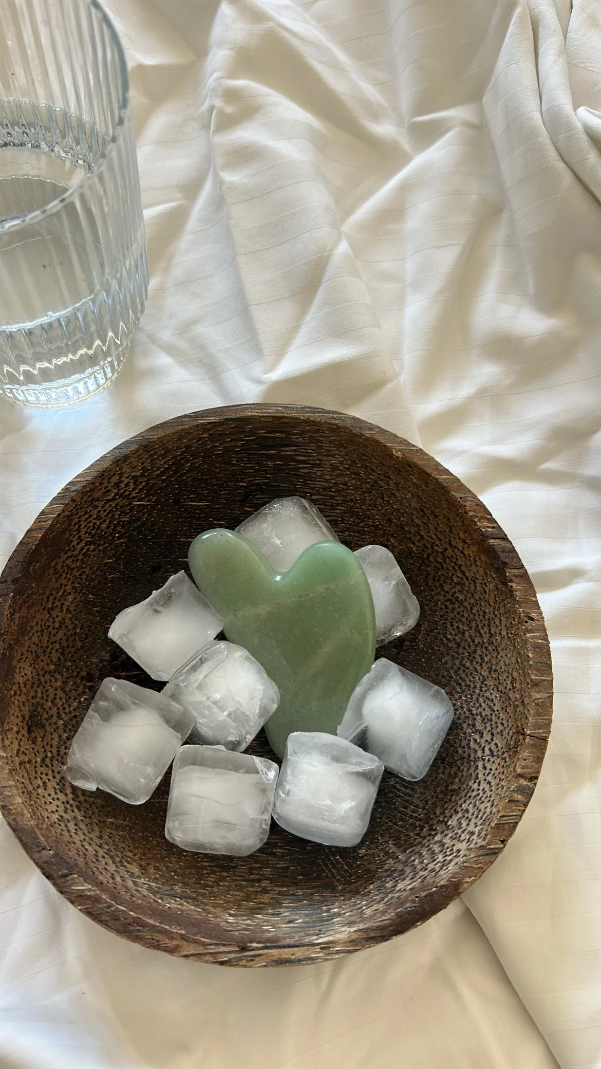 Gua sha tool resting in a wooden bowl with ice, representing supportive body therapy and recovery