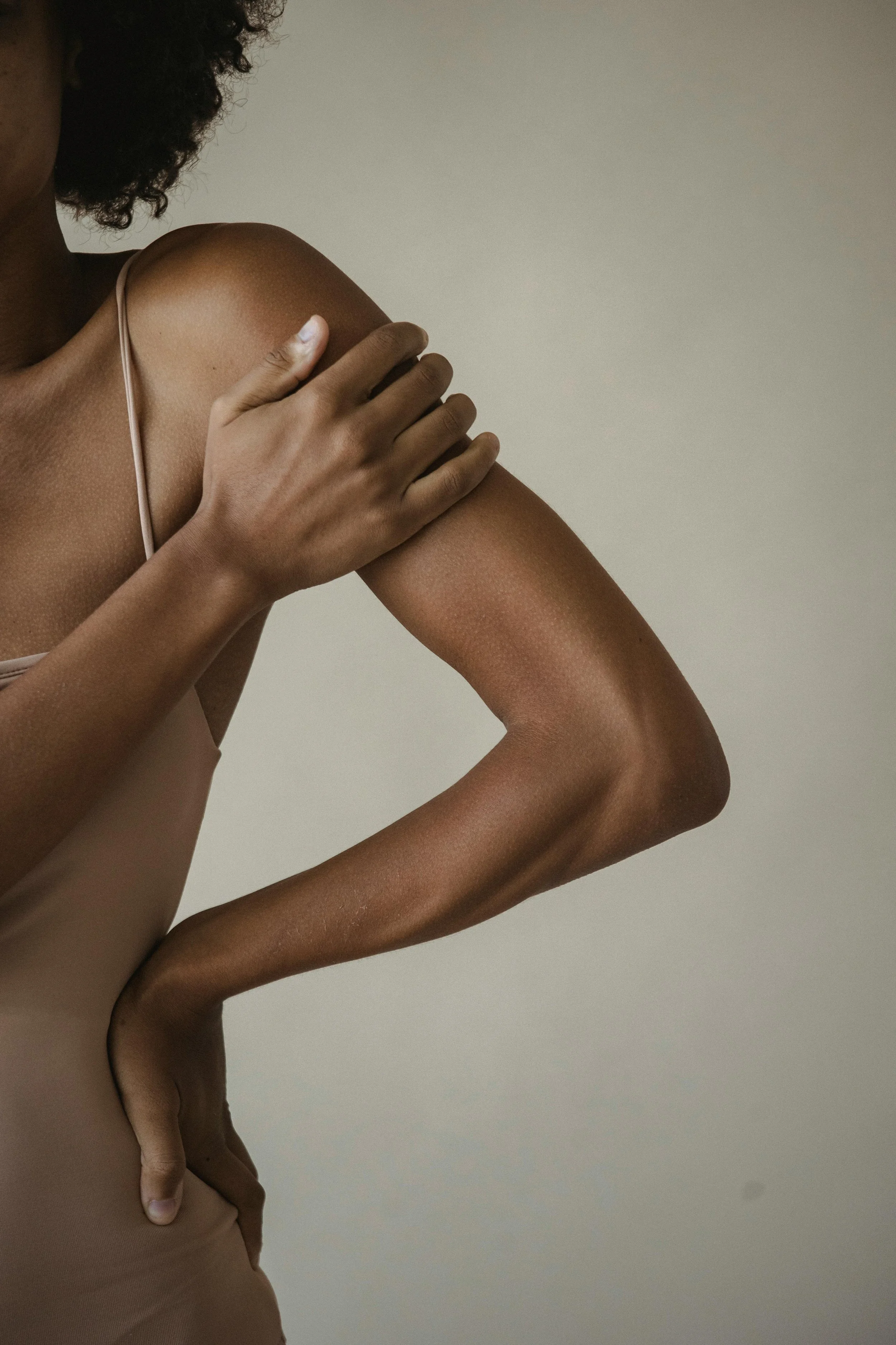 Woman holding her shoulder, representing chiropractic questions and body tension support