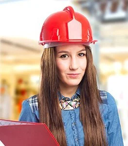 Vrouw met lange bruingewassen haar, draag een rode bouwhelmd en een blauwe blouse, houdt een rode map.