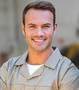 Man met korte bruin haar, glimlachend, in een lichte blouse, op de achtergrond een neutrale muur.