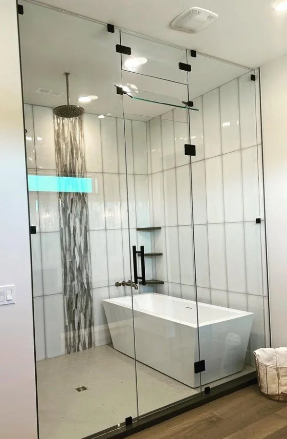 Modern bathroom with a walk-in shower enclosed by glass panels, featuring a rain shower head, a standalone bathtub, and built-in wall shelves.