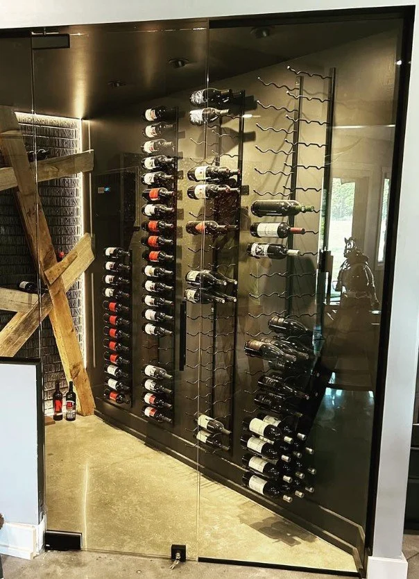 A glass wine cabinet with bottles stored on metal racks inside.