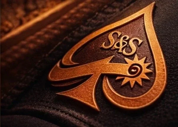 Close-up of a leather patch with the initials 'S&S' and a star symbol on a dark fabric surface.
