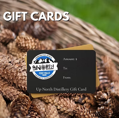 Black gift card for Up North Distillery on a bed of pinecones, with the text "GIFT CARDS" in white at the top.