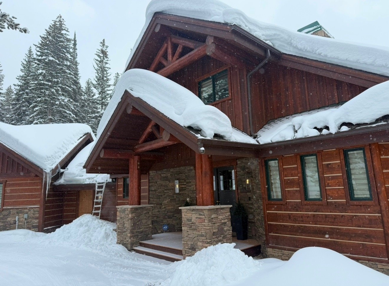 Heavy snow load on the roof of a timber and stone Colorado mountain home before heat trace installation