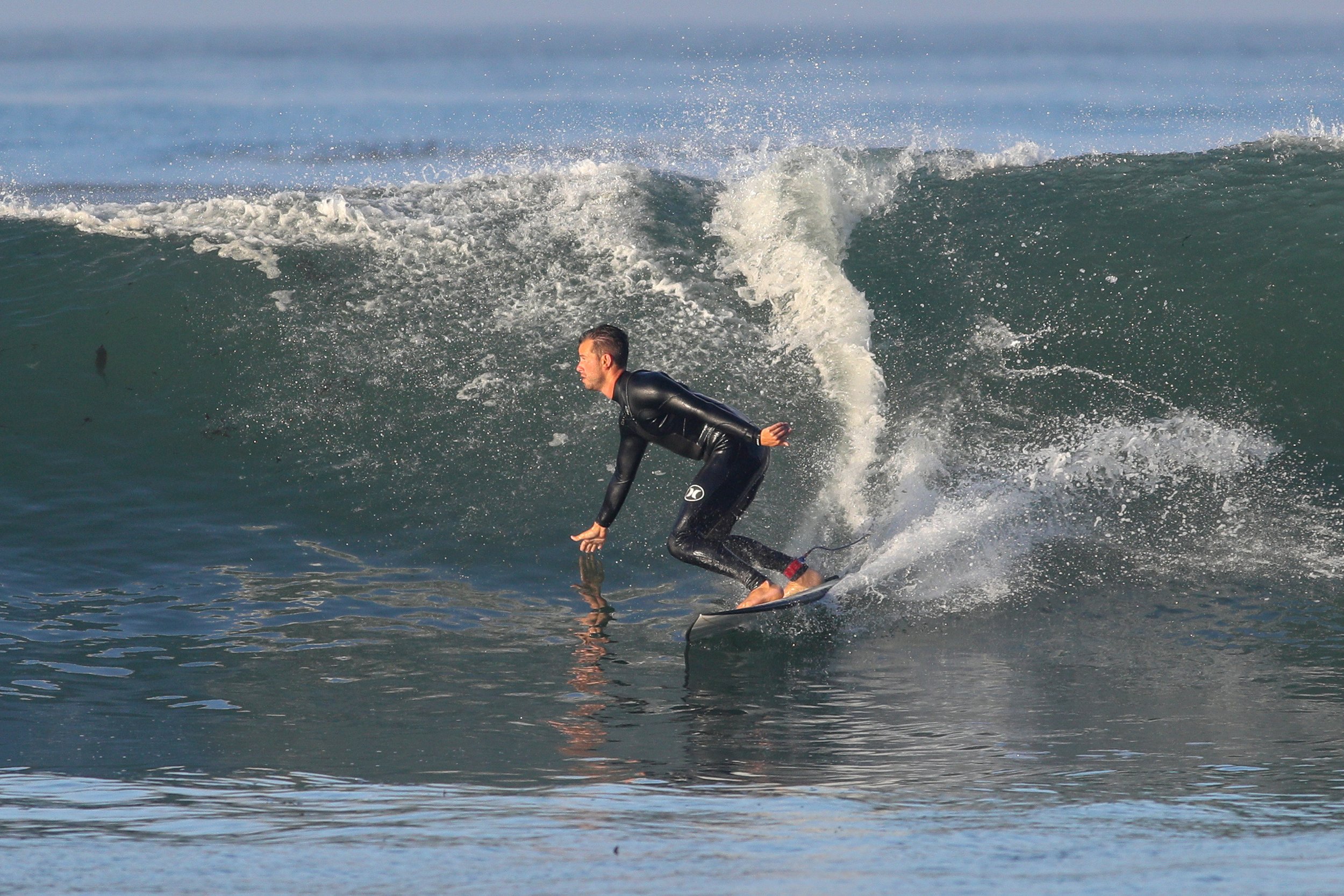 A man wearing a wetsuit surfing on a wave in the ocean.