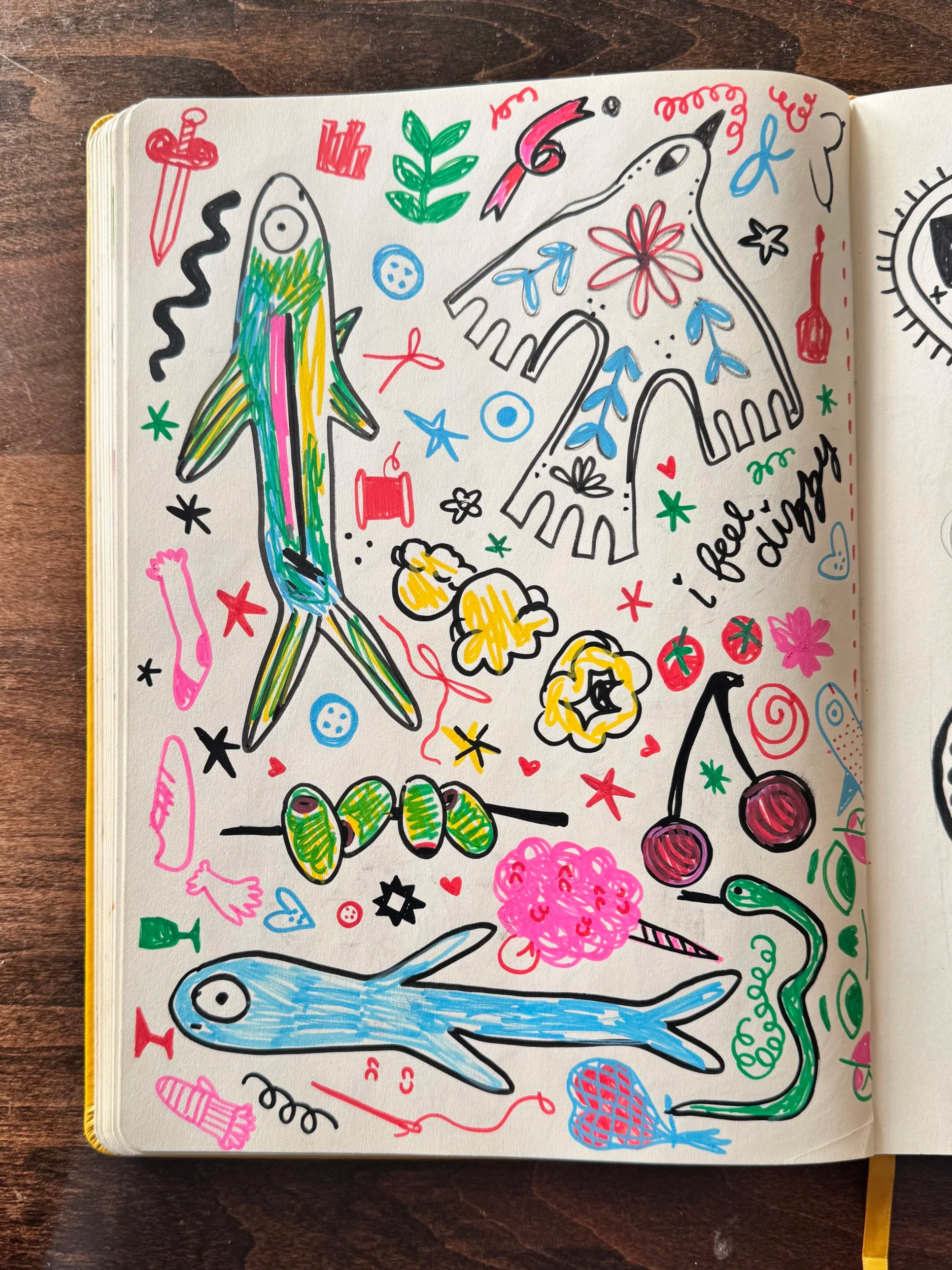 Colorful doodles of fish, a snake, cherries, popcorn, a mushroom, a flower, a leaf, buttons, a heart, a star, and confetti on a white page with the handwritten phrase "i feel..dizzy".