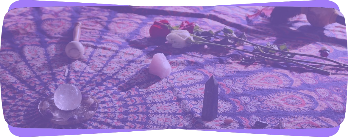 Roses, crystals, and candles laid out on a patterned cloth, suggesting a ritual or spiritual setting.