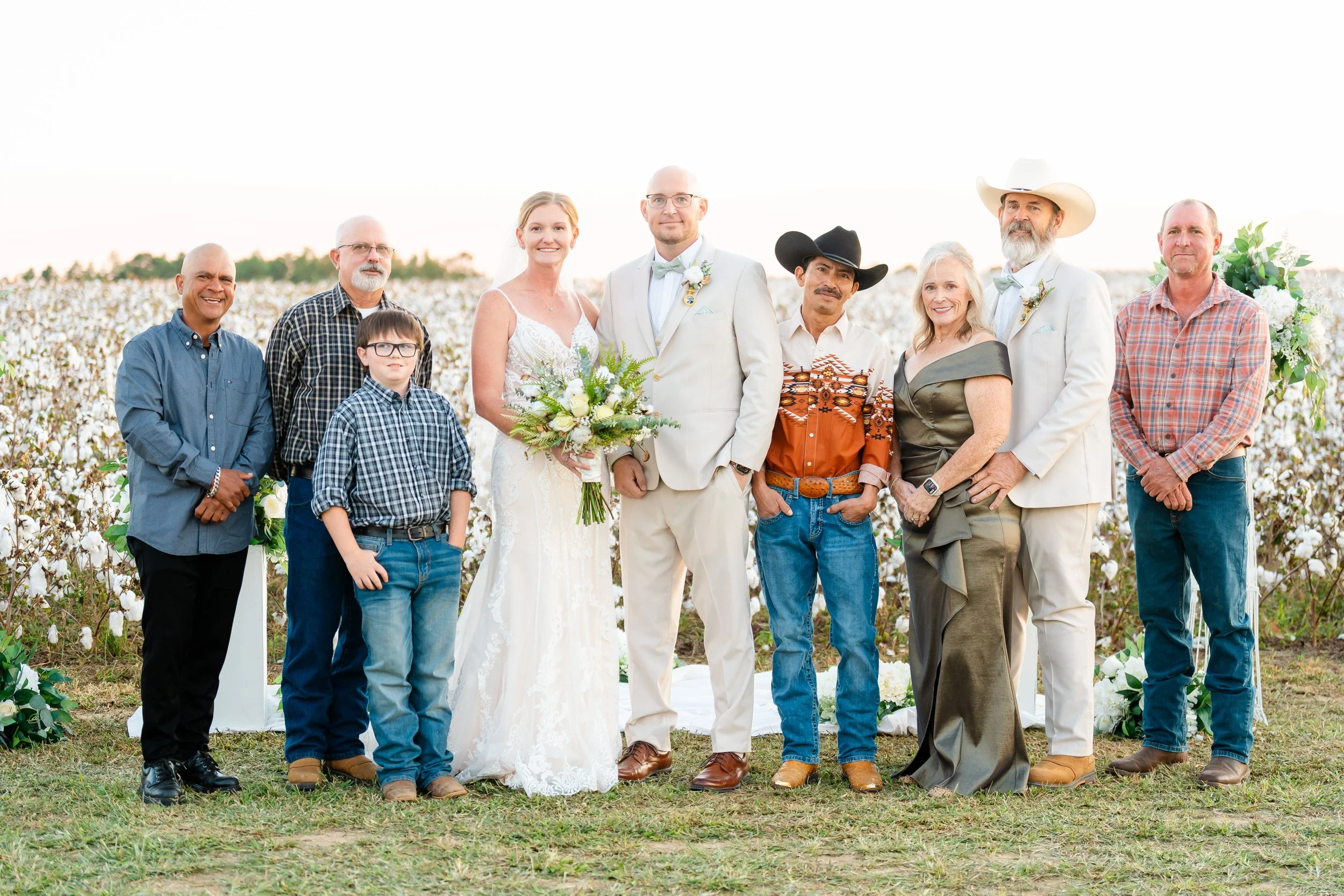 The Holt Family Family and friends standing outdoors in cotton field during a wedding celebration.