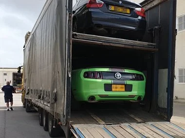 Bright green, UK registered Ford Mustang Convertible arrives at our workshop in Murcia, Spain on covered transporter. This ex USA left hand drive vehicle will require an individual homologation test prior to import inspection as it does not have Euro
