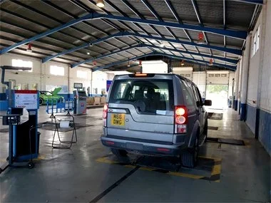 Landrover Discovery from Malaga region undergoes rear brake test on rolling road at ITV station in Lorca. This vehicle would require unexpected workshop time to fix and align front headlights that had possibly been damaged at a Landrover dealer in th