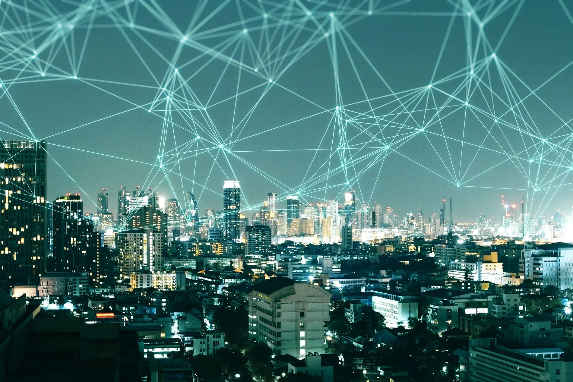 Night cityscape with illuminated buildings and a digital network overlay of interconnected lines and points above the skyline.