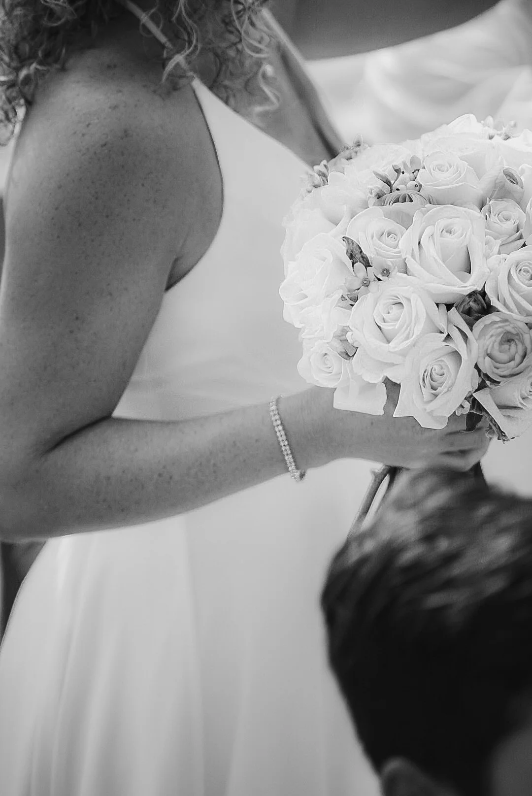 A bride in a wedding dress holding a bouquet of roses during a wedding ceremony.