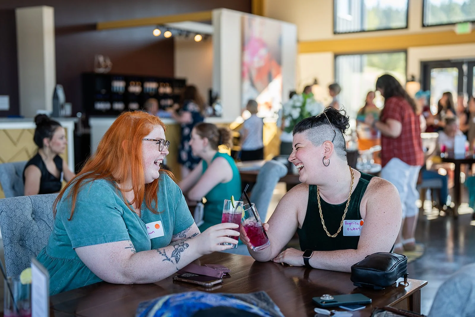 Two women laughing and cheering drinks at a local winery in Southern Oregon.