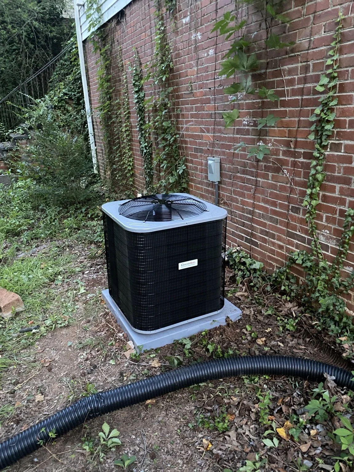Black outdoor air-conditioning condenser beside a brick home in Upstate South Carolina