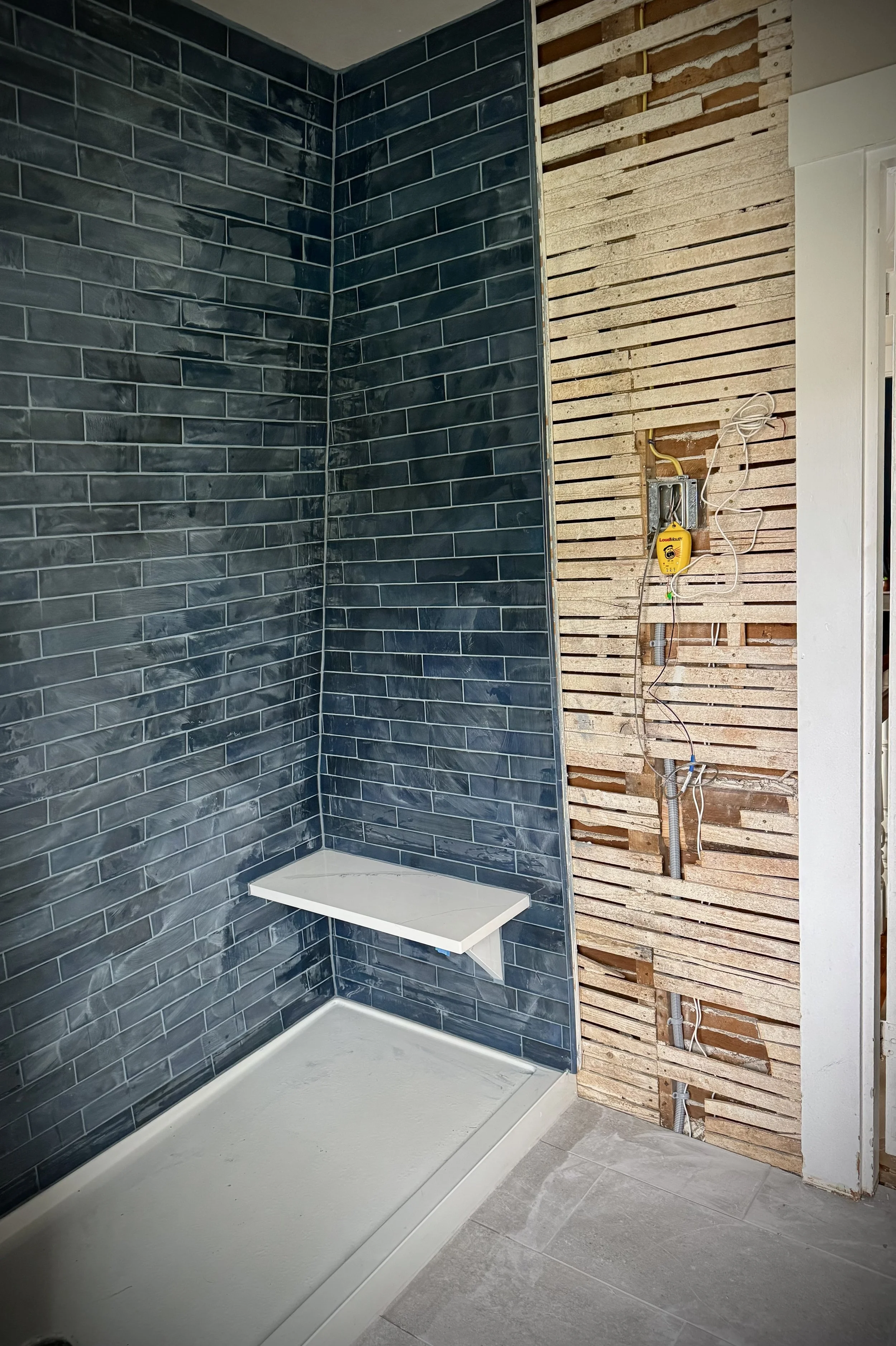 custom tile shower with built-in shelf and unfinished wall