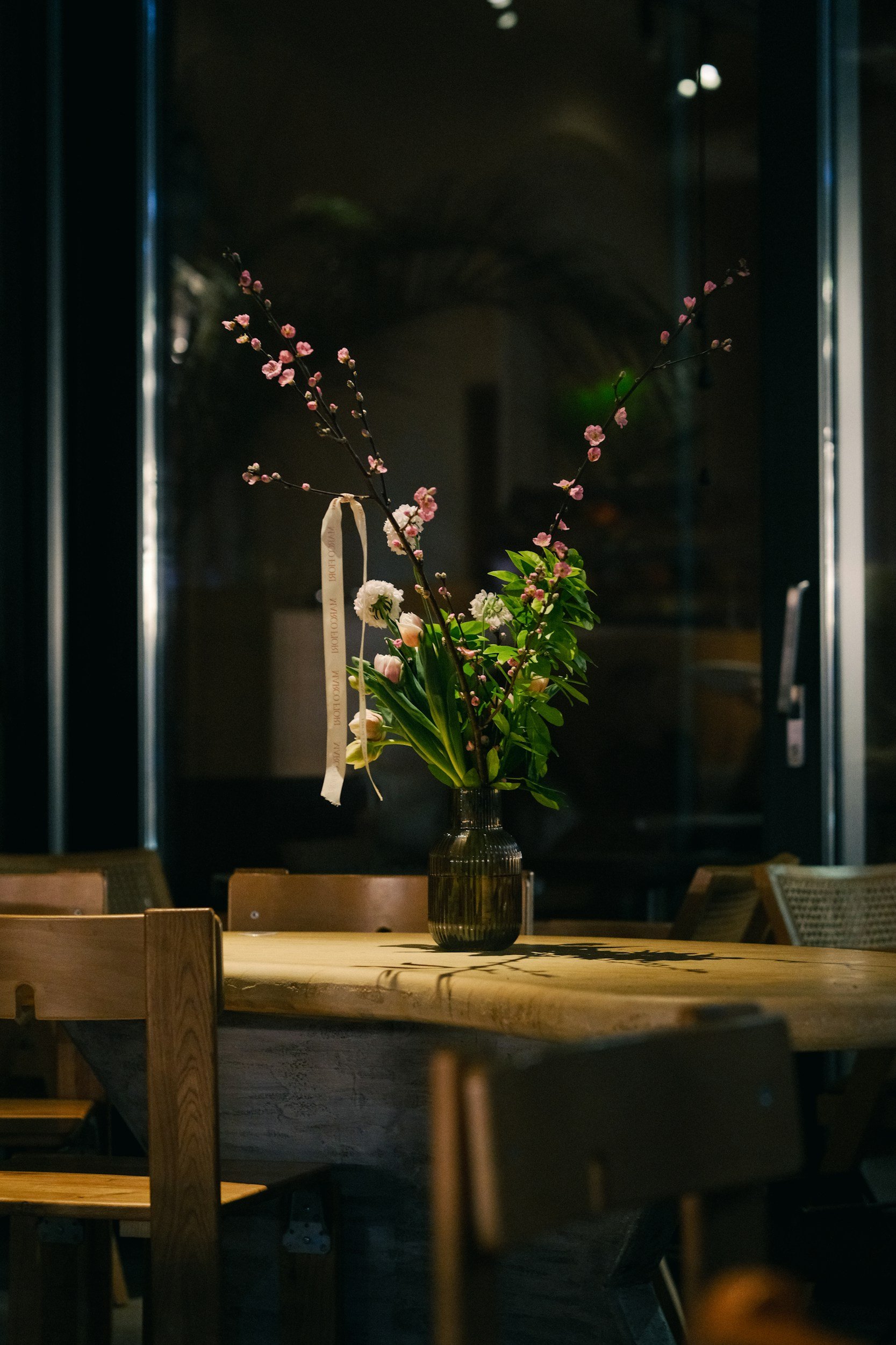 Un vase avec des fleurs sur une table en bois dans une pièce sombre