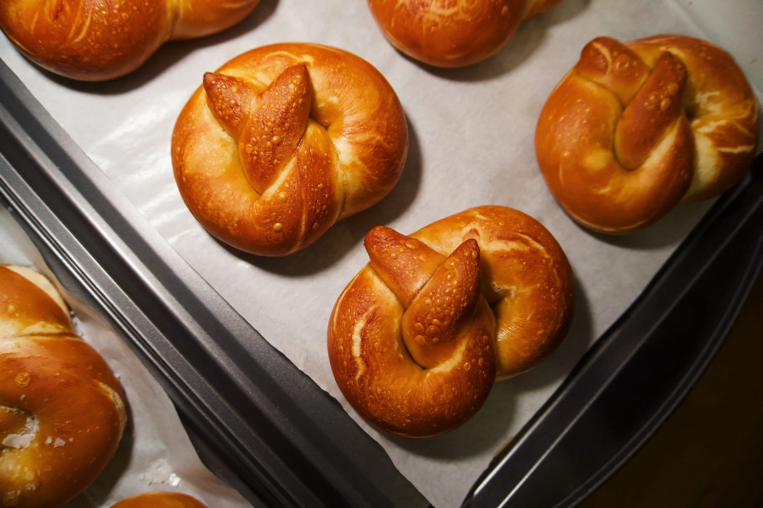 Baked pretzels shaped like knots on a baking sheet lined with parchment paper.